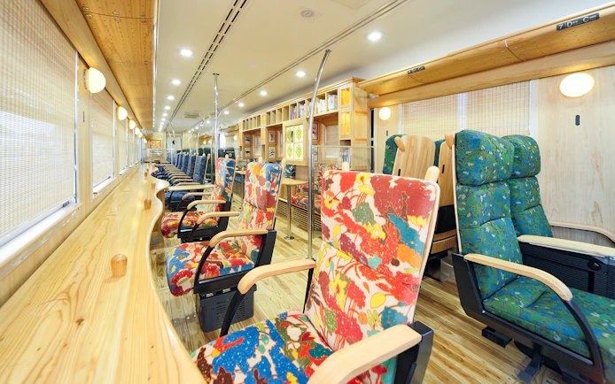 Colorful train interior with patterned seats and wooden decor, Kyushu, Japan.