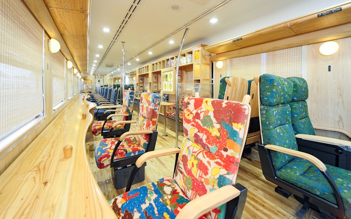 Colorful train interior with patterned seats and wooden decor, Kyushu, Japan.