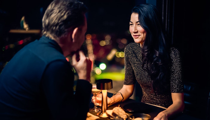 Couple dining at Melbourne Skydeck with city lights in the background.