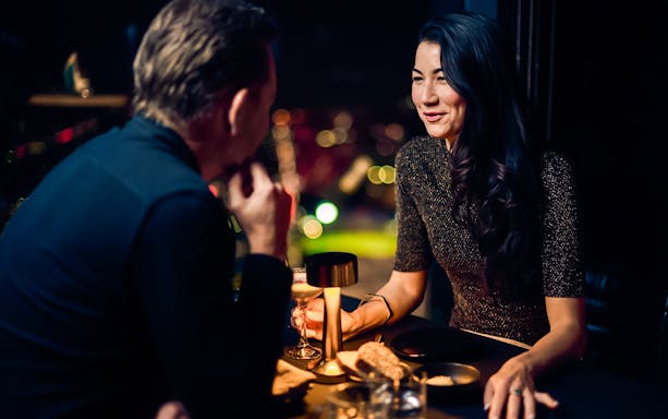 Couple dining at Melbourne Skydeck with city skyline view.