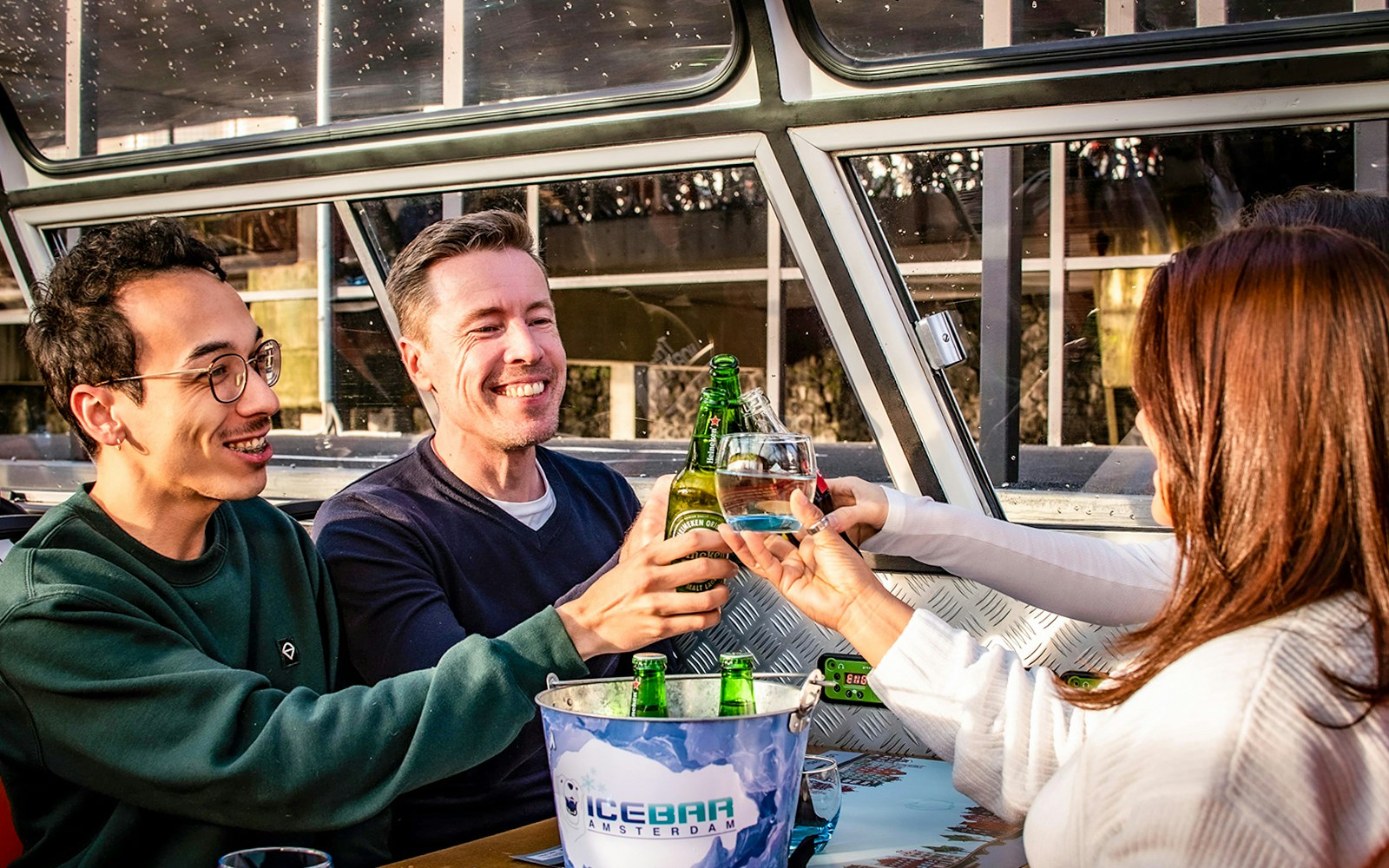 Amsterdam canal cruise with pizza and drinks, view of historic buildings and bridges.