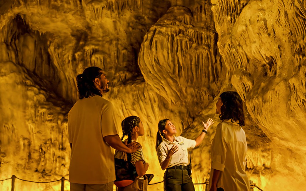 Family exploring The Cavern in Rainforest Wild ASIA with a guide.