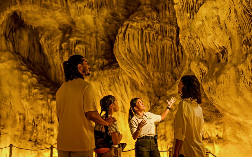 Family exploring The Cavern in Rainforest Wild ASIA with a guide.