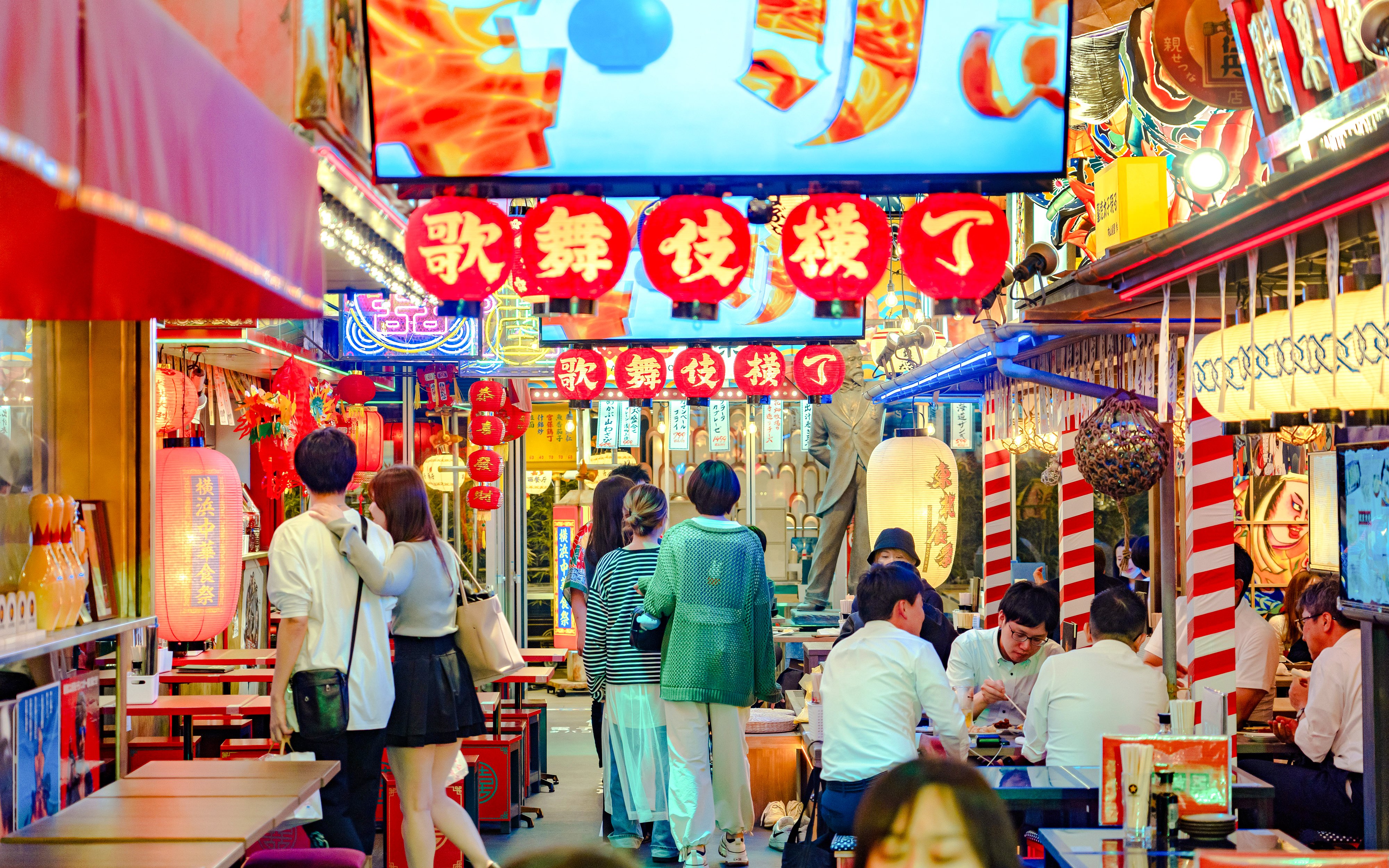 Tokyo street with vibrant lanterns and people dining, capturing local culture.
