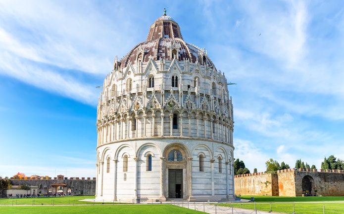 Pisa Baptistery with guided tour group in foreground, Leaning Tower visible in background.