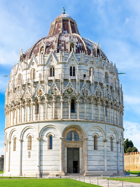Pisa Baptistery with guided tour group in foreground, Leaning Tower visible in background.