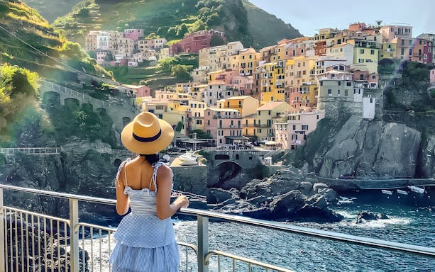 Woman overlooking colorful buildings in Manarola, Cinque Terre, Italy.