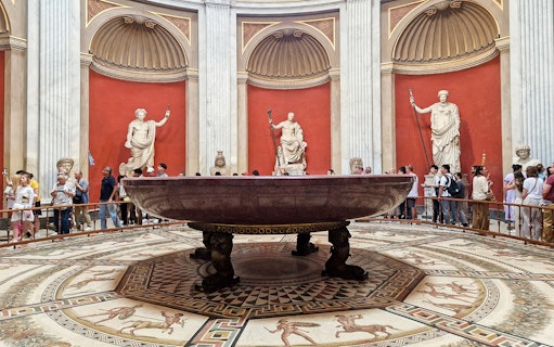 Sala Rotonda in the Vatican Museums with ancient statues and a large marble basin.