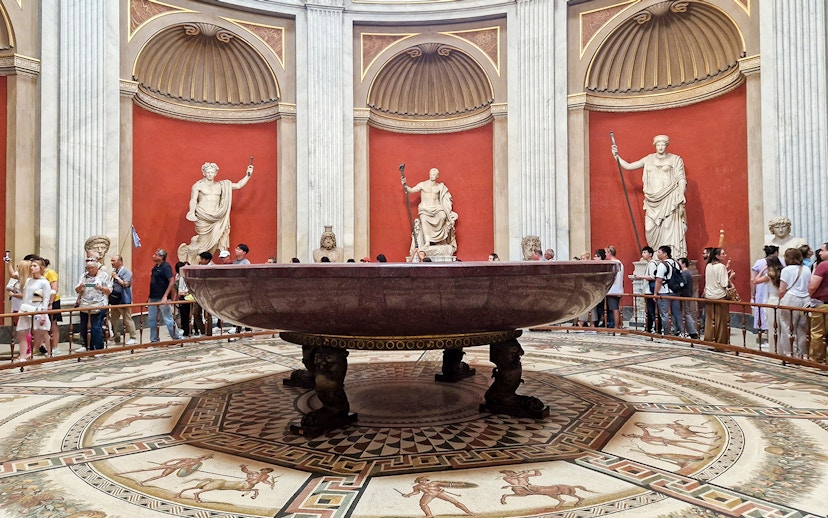 Sala Rotonda in the Vatican Museums with ancient statues and a large marble basin.
