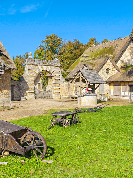 Rustic village scene at Marie-Antoinette's Domain, Versailles, with stone cottages and wooden carts.
