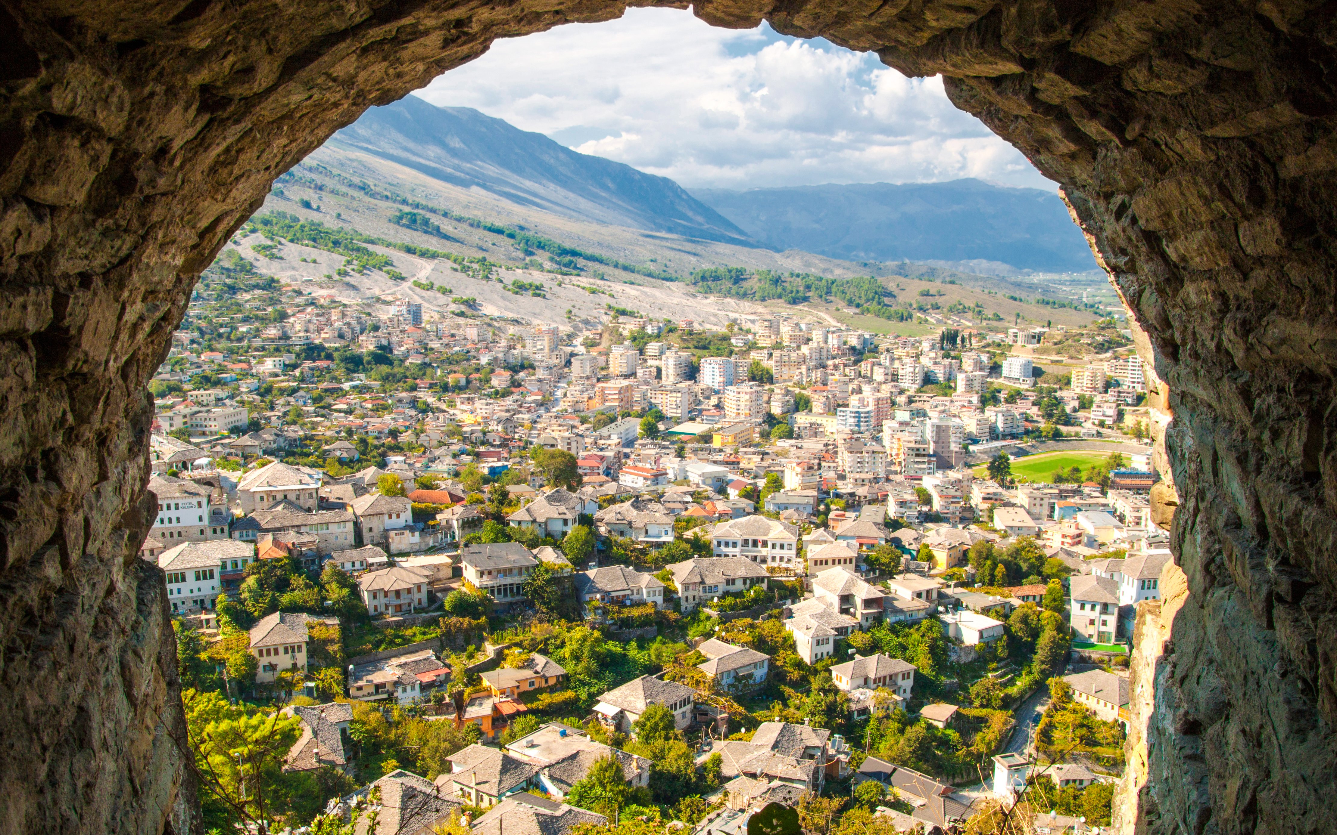 View of Old Town Gjirokaster from the castle, showcasing historic stone houses and surrounding landscape.