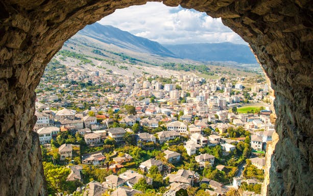 View of Old Town Gjirokaster from the castle, showcasing historic stone houses and surrounding landscape.