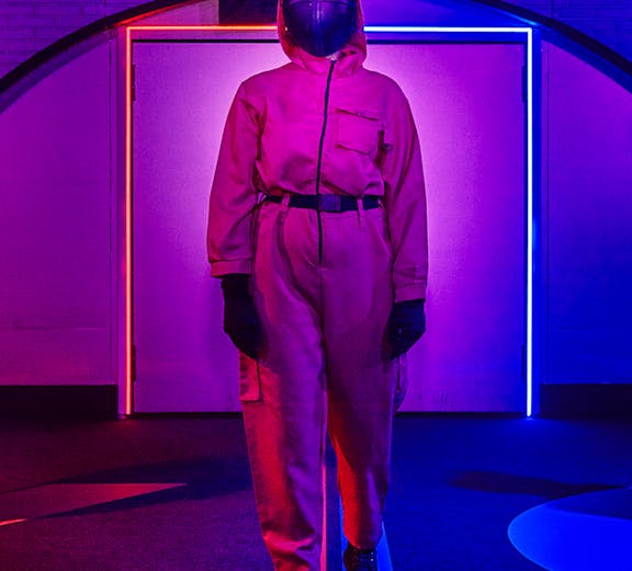 Person in pink jumpsuit and mask at Squid Games experience in London.