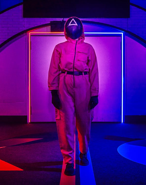 Person in pink jumpsuit and mask at Squid Games experience in London.