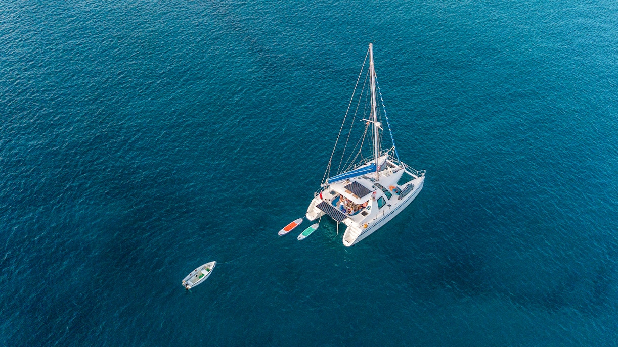 Aerial view of a catamaran with paddleboards in open water.