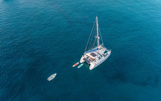 Aerial view of a catamaran with paddleboards in open water.