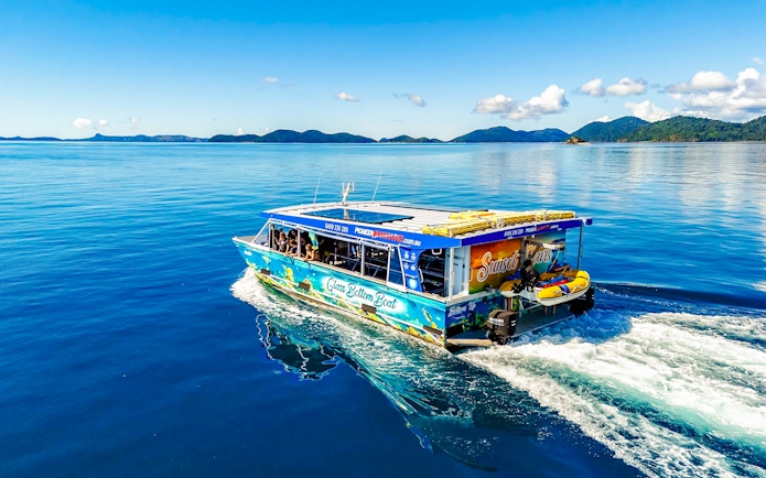 Glass bottom boat cruising near Airlie Beach with scenic island views.