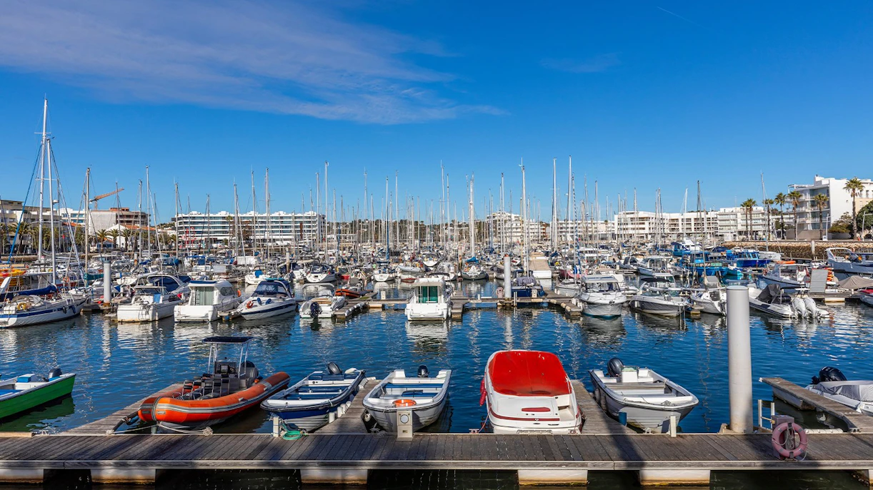 Boats docked at Marina of Lagos with waterfront cityscape in Algarve, Portugal.
