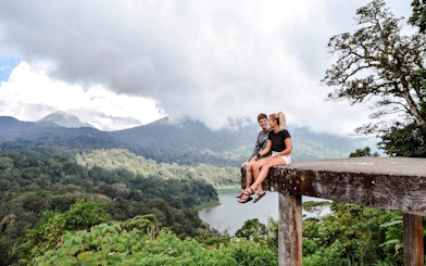 Couple sitting on a ledge overlooking jungle and lake in Bali.