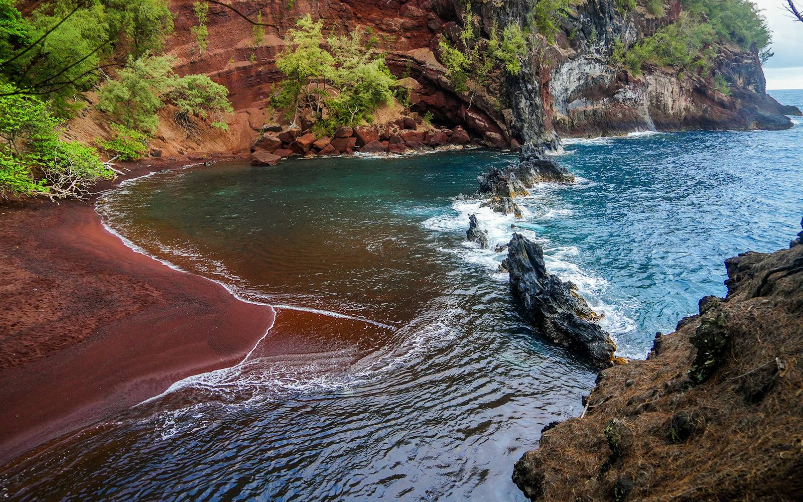 Kaihalulu Red Sand Beach with red cliffs and turquoise water on the Road to Hana, Maui.