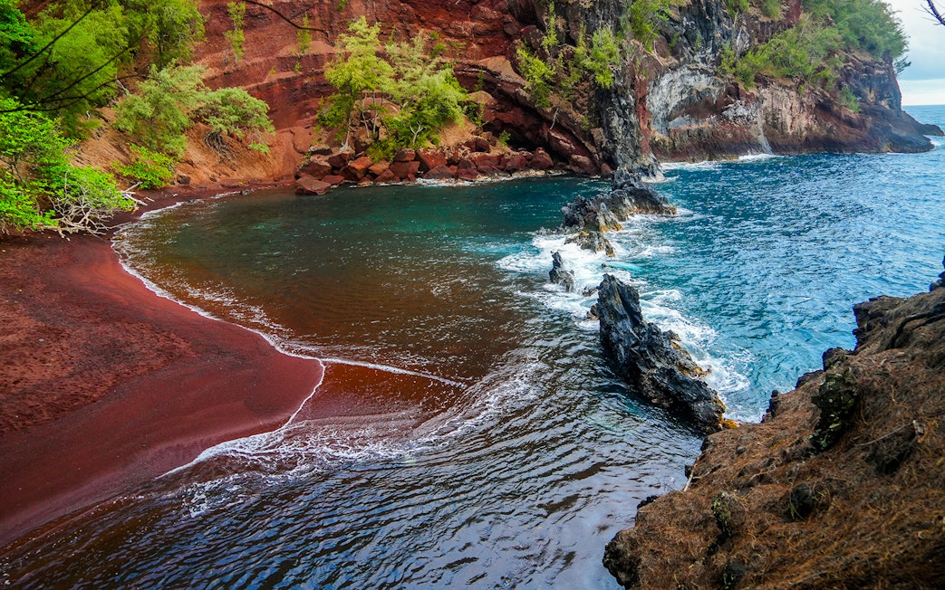 Kaihalulu Red Sand Beach with red cliffs and turquoise water on the Road to Hana, Maui.
