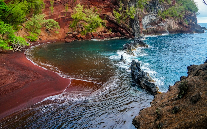 Kaihalulu Red Sand Beach with red cliffs and turquoise water on the Road to Hana, Maui.