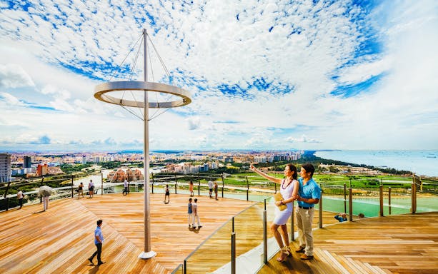 Tourists enjoying the view from Marina Bay Sands SkyPark Observation Deck in Singapore.