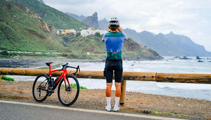 Cyclist overlooking ocean and mountains on Tenerife cycling tour.