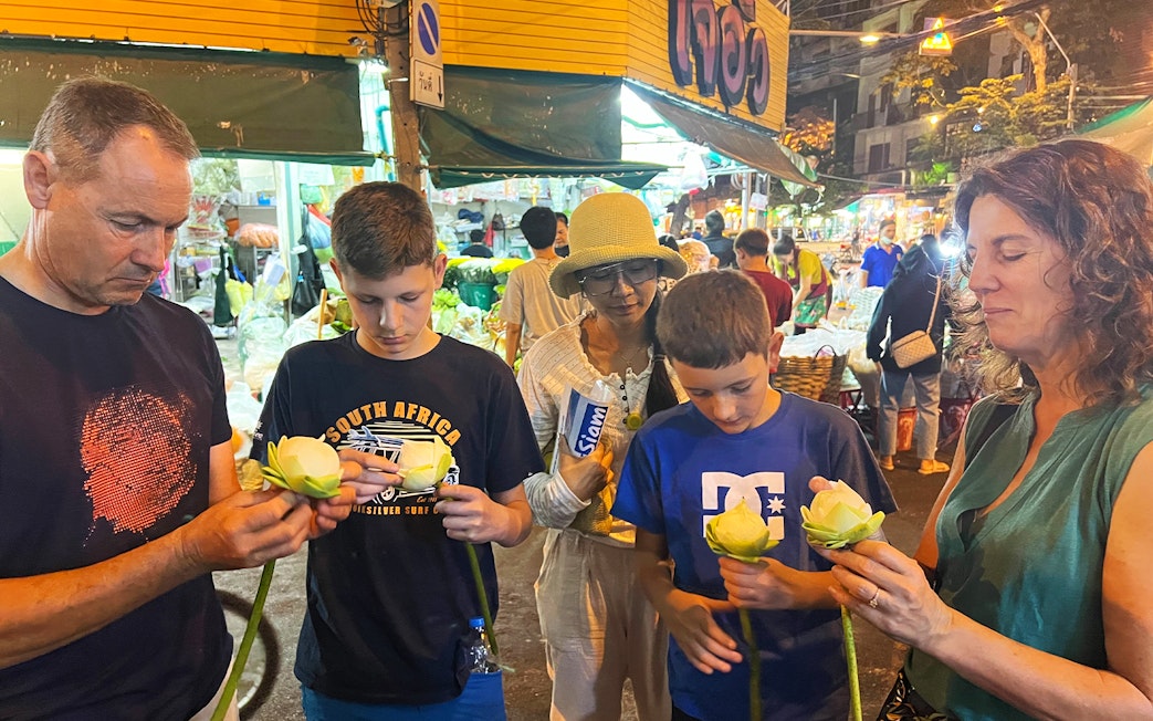 Family folding lotus flowers during Bangkok Tuk-Tuk night tour with Chinatown street food.