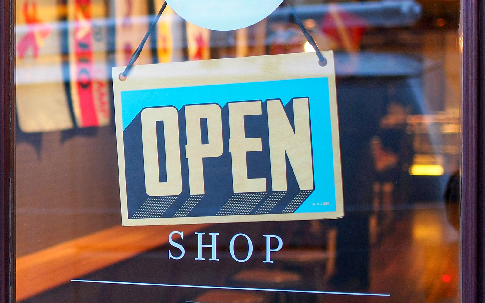 Open sign hanging on shop window in city center.