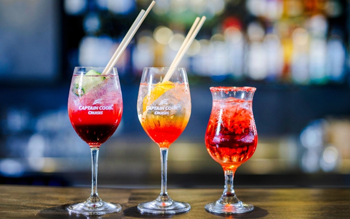 Three colorful cocktails on Captain Cook Cruises glasses for Vivid Sydney dinner cruise.