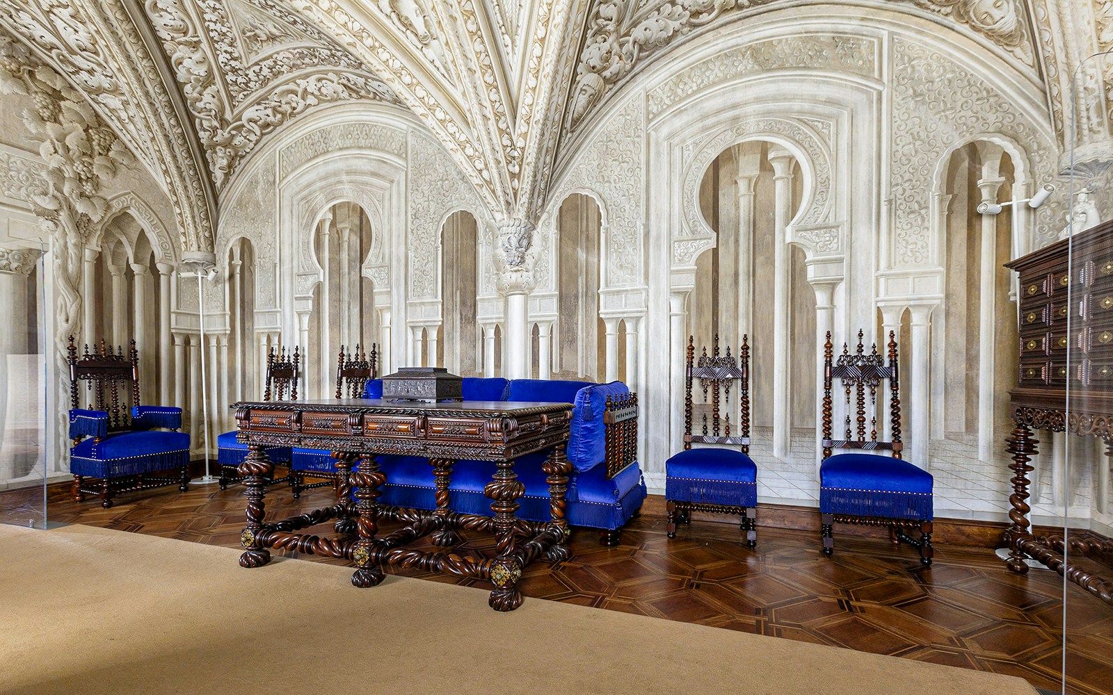 Ornate sitting room in Pena Palace with carved wooden furniture and blue upholstery.