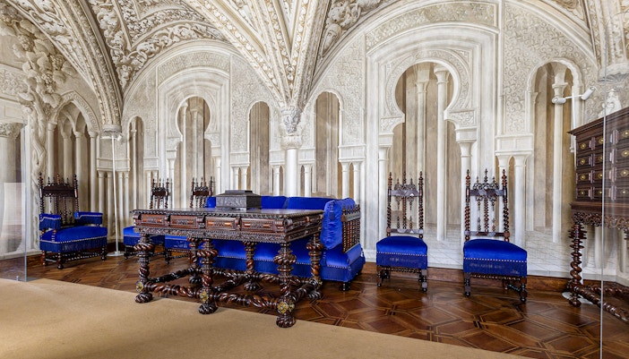 Ornate sitting room in Pena Palace with carved wooden furniture and blue upholstery.