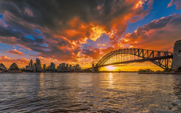 Sydney Harbour Bridge and Opera House at sunset, view from the water, True Crime Cruise.
