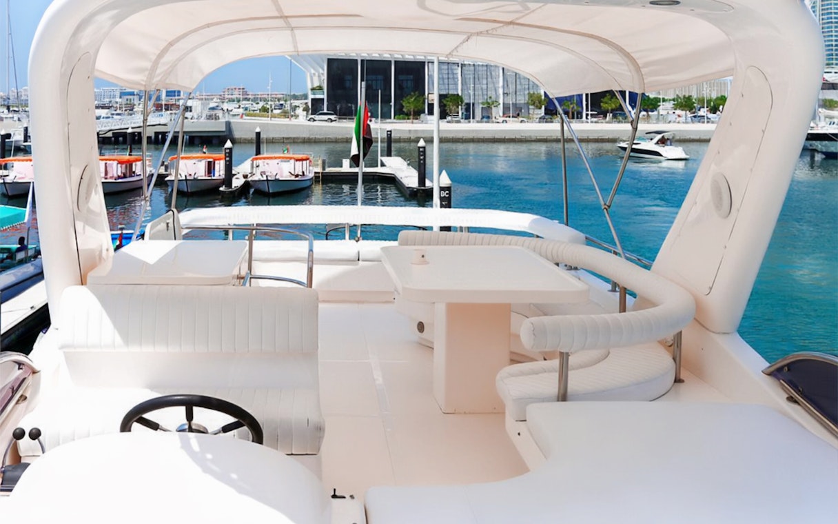 Luxury yacht deck with seating, docked in Dubai Marina.