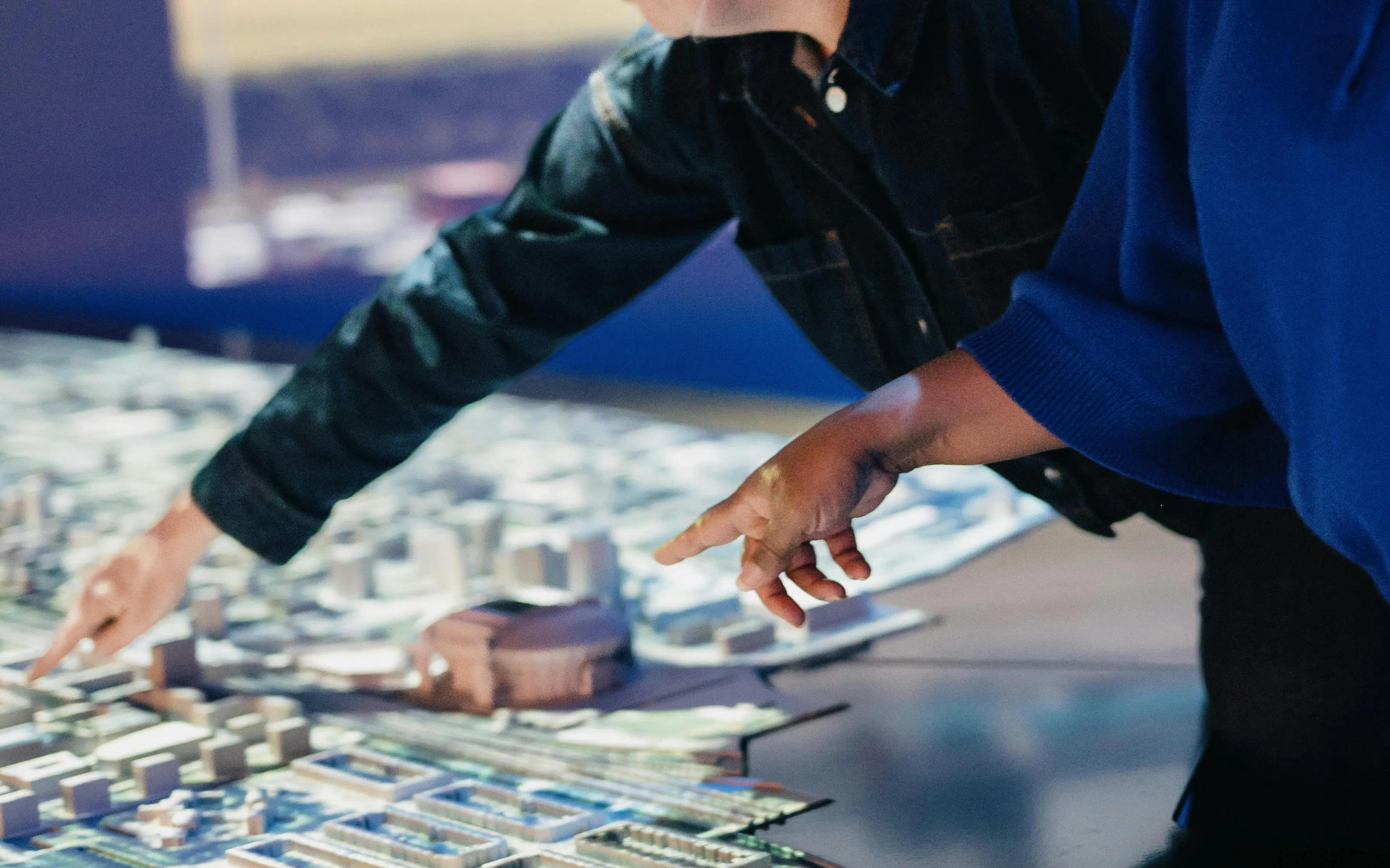 People examining a detailed model of Amsterdam city layout.