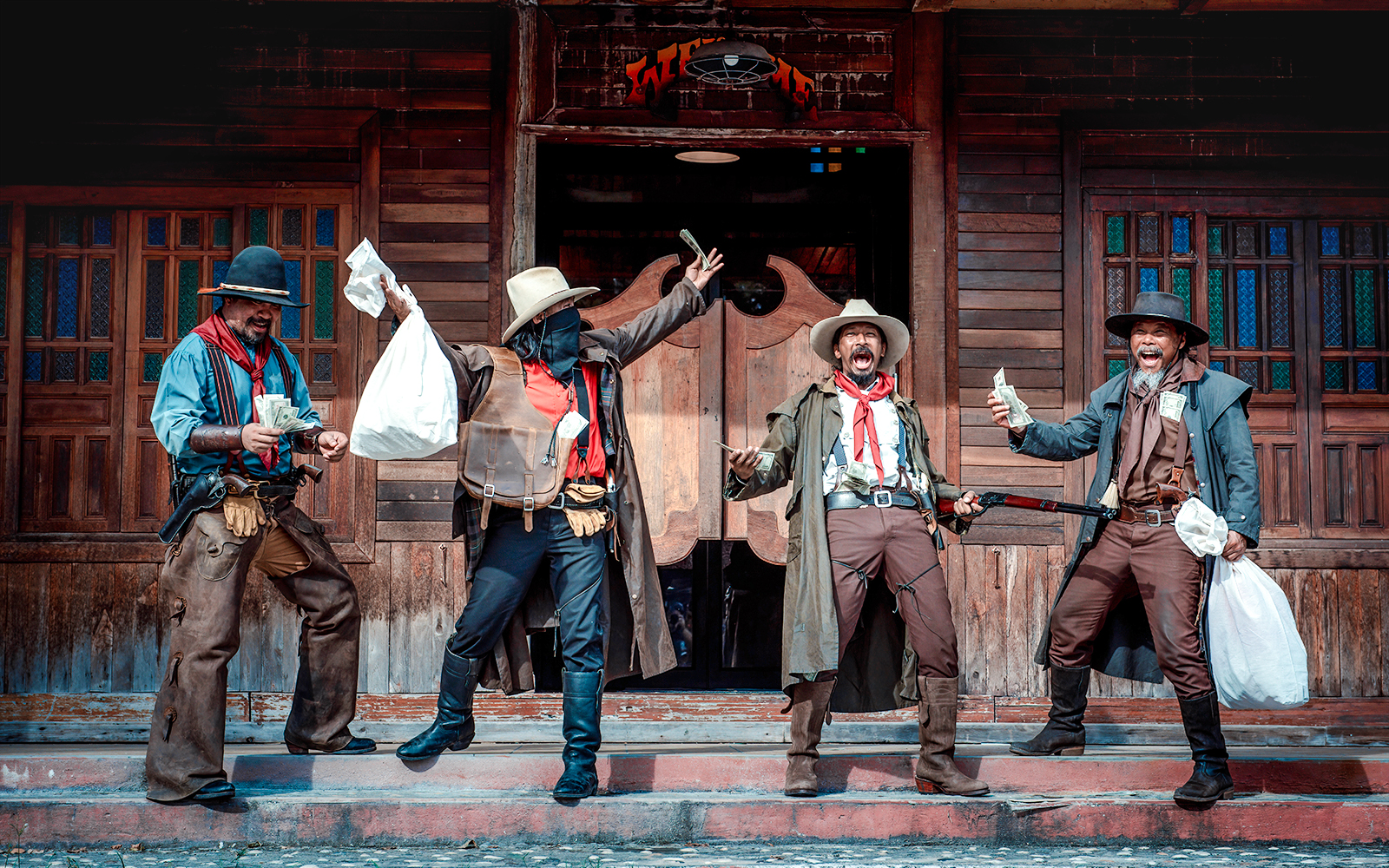 Cowboys performing a Wild West show with money and props in front of a saloon.