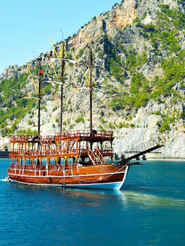 Tour boat sailing through Green Canyon with rocky cliffs in the background.