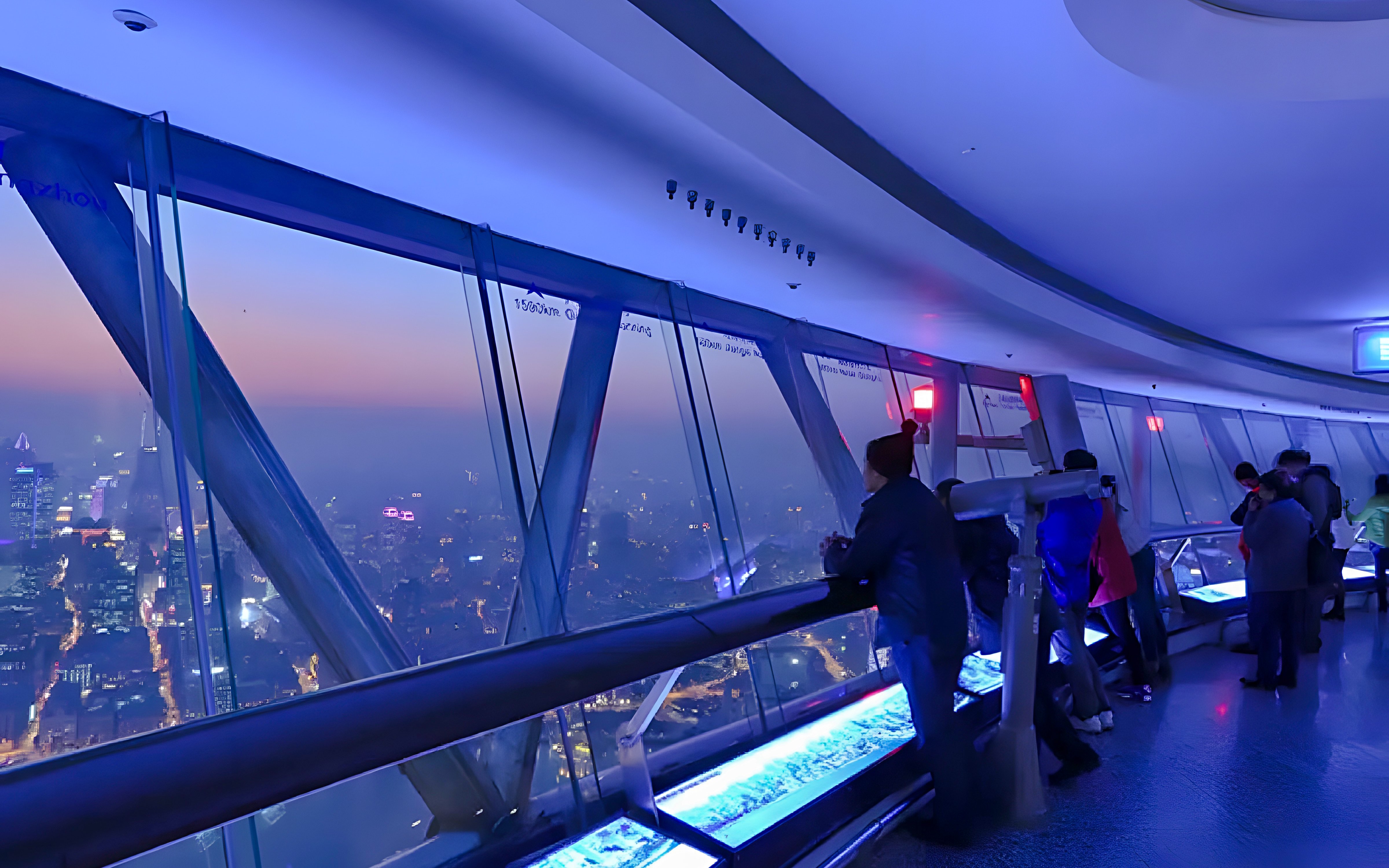 Visitors at the Oriental Pearl Tower observation deck, Shanghai, viewing city skyline.