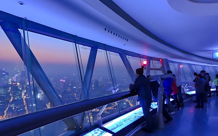 Visitors at the Oriental Pearl Tower observation deck, Shanghai, viewing city skyline.