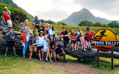 Group enjoying Jurassic Valley at Kualoa Ranch, Hawaii with mountains in the background.