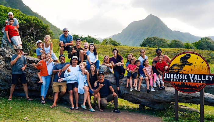 Group enjoying Jurassic Valley at Kualoa Ranch, Hawaii with mountains in the background.