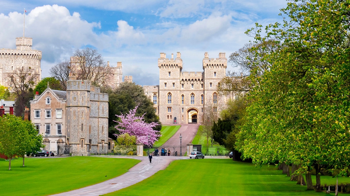 Windsor Castle exterior with lush green lawns and a pathway leading to the entrance.