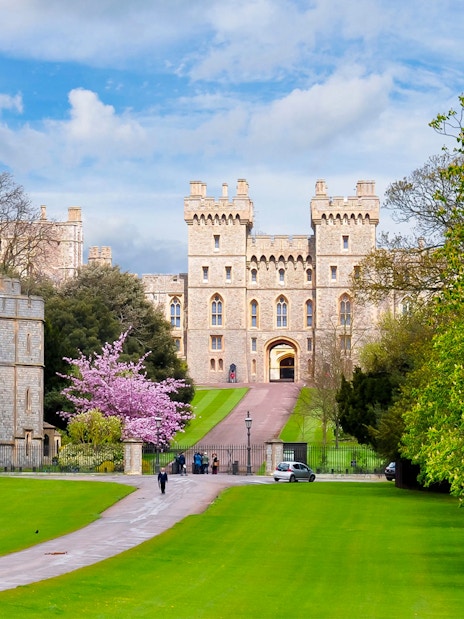 Windsor Castle exterior with lush green lawns and a pathway leading to the entrance.