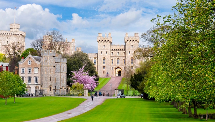 Windsor Castle exterior with lush green lawns and a pathway leading to the entrance.