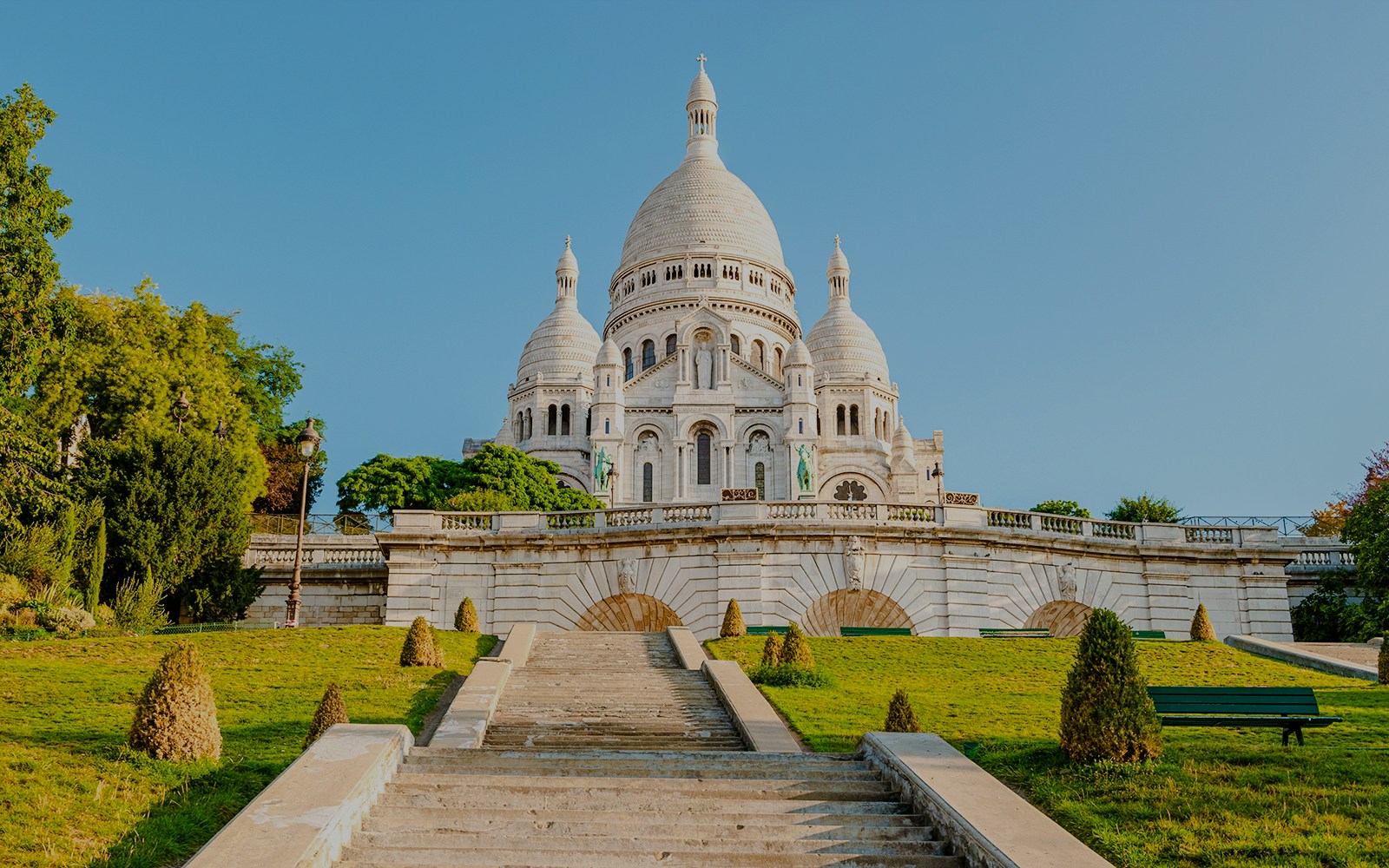 Sacré-Cœur Basilica exterior with steps and greenery in Paris, France.