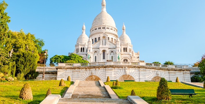 Sacré-Cœur Basilica exterior with steps and greenery in Paris, France.