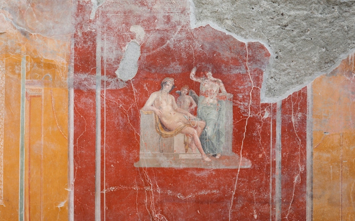 Ancient fresco depicting mythological figures in Pompeii ruins.