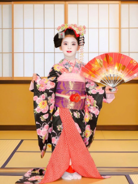 Maiko in traditional kimono holding a fan during a photoshoot in Kyoto.