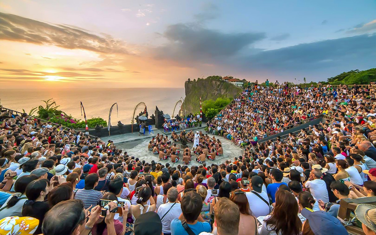 Open-air Kecak dance performance at Uluwatu Temple, Bali, with ocean sunset backdrop.